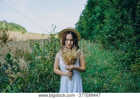 Beautiful Girl In A White Dress With A Bouquet Of Dried Flowers. Young Woman In A Green Park. Girl I