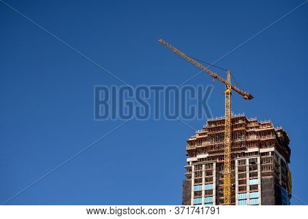 Skyscraper With Yellow Crane On A Blue Sky