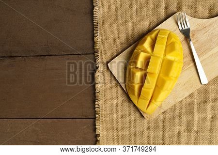 Top View Yellow Half  Mango With Small Fork. Mango Fruit Cubes On The Wooden Table. Tropical Fruit A
