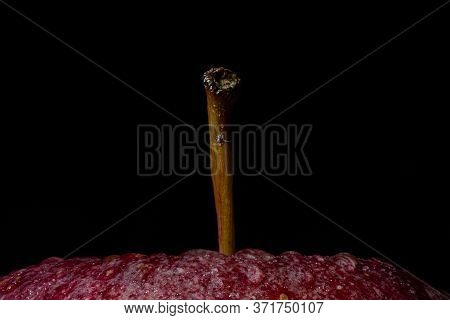 Closeup Of The Upper Part Of A Juicy Red Apple With Water Drops Against A Black Background