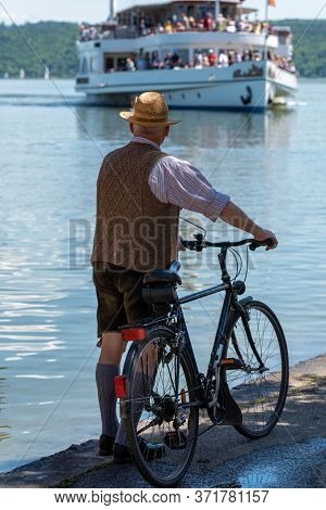 Male Dressed With Lederhose At The Dießen Harbor Looking On A Ship