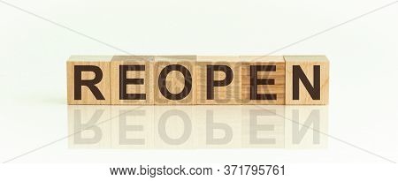Wooden Blocks With The Text: Reopen. The Text Is Written In Black Letters And Is Reflected In The Mi