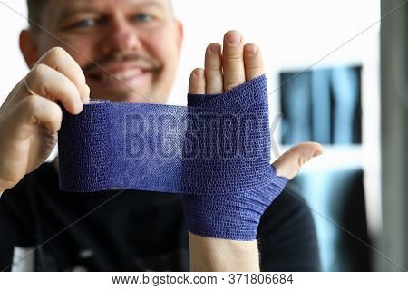 Smiling Man Rewinds His Hand With Bandage An Injury. Bandage Is Used For Dystrophic And Inflammatory