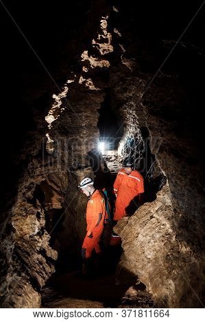 Two Men, Strong Physique, Explore The Cave. Men Dressed In Special Clothes To Pass Through The Cave 