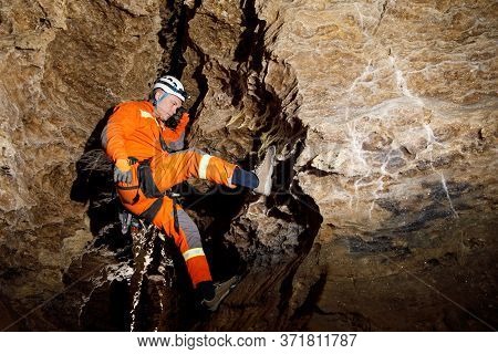 Speleologist Descend By The Rope In The Deep Vertical Cave Tunnel.