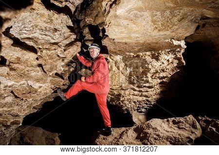 Man Walking And Exploring Dark Cave With Light Headlamp Underground.