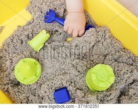 A Child Plays With Kinetic Sand: Closeup Of A Child's Hand And Sand. Educational Games With Children