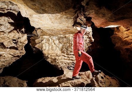 Man Walking And Exploring Dark Cave With Light Headlamp Underground.