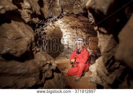 Man Walking And Exploring Dark Cave With Light Headlamp Underground.