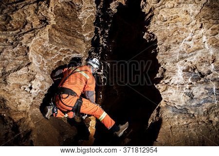 Speleologist Descend By The Rope In The Deep Vertical Cave Tunnel.