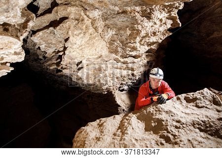 Man Walking And Exploring Dark Cave With Light Headlamp Underground.