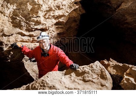 Man Walking And Exploring Dark Cave With Light Headlamp Underground.