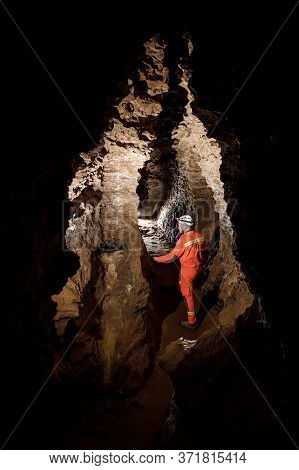 Man Walking And Exploring Dark Cave With Light Headlamp Underground.