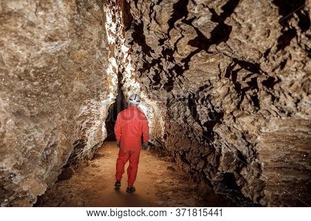 Man Walking And Exploring Dark Cave With Light Headlamp Underground.