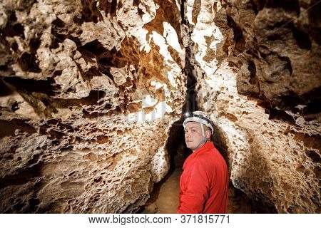 Man Walking And Exploring Dark Cave With Light Headlamp Underground.