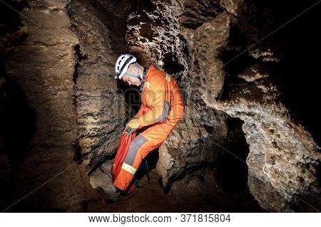 Man Walking And Exploring Dark Cave With Light Headlamp Underground.