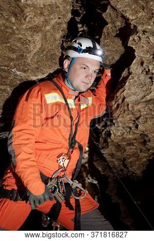 Speleologist Descend By The Rope In The Deep Vertical Cave Tunnel.