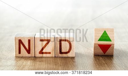 Wooden Blocks With The Inscription Nzd And A Block Symbolizing The Rise And Fall Of Financial Market