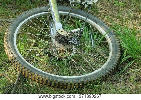 Part Of A Gray Bicycle Wheel With A Rim And Knitting Needles On The Grass In The Park