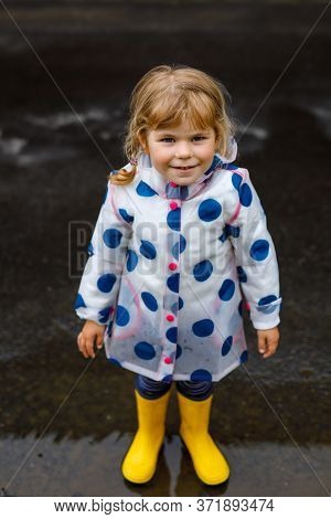 Little Toddler Girl Wearing Yellow Rain Boots, Running And Walking During Sleet On Rainy Cloudy Day.