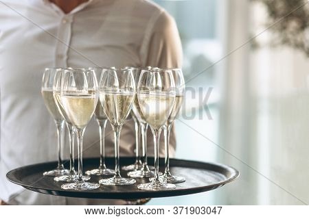 The Waiter Is Holding A Tray With Glasses Of Champagne Or White Sparkling Wine. Service In The Resta