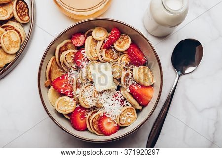 Trendy Home Breakfast With Tiny Cereal Pancakes With Piece Of Butter, Coconut Shreds And Fresh Straw
