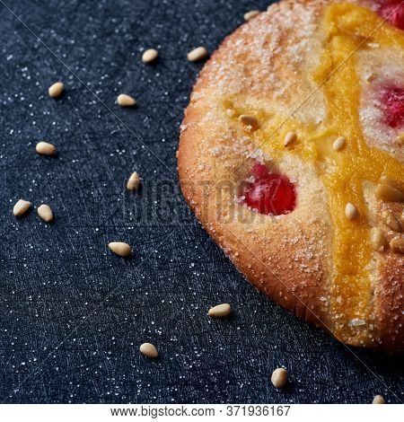 closeup of a coca de Sant Joan, a typical sweet flat cake from Catalonia, Spain, eaten on Saint Johns Eve, on a black fabric surface sprinkled with pine nuts