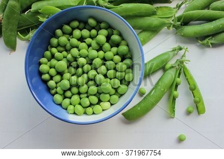 Fresh Peeled Green Sugar Snap Peas In A Bowl And Open Pods On A White Wooden Table Background With C