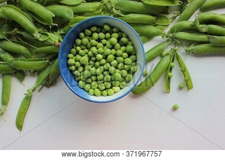 Fresh Peeled Green Sugar Snap Peas In A Bowl And Open Pods On A White Wooden Table Background With C