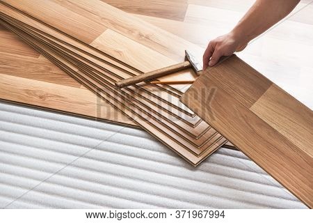 Installing Laminated Floor, Detail On Man Hands Holding Wooden Tile, Over White Foam Base Layer