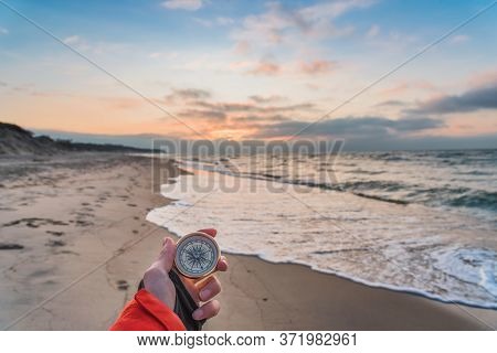 First-person View Of A Female Hand With A Compass On A Background Of A Beautiful Sea Landscape. The 