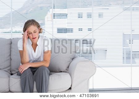 坐在沙发上和获取 headhache 的女商人
