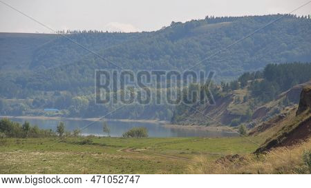 Steep Red Clay Shores Of The Lake Covered With Coniferous Forest On A Hot Summer Day