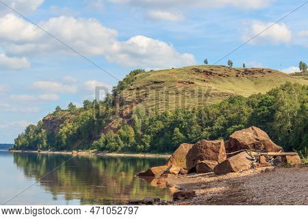 Steep Red Shores Of The Lake Covered With Coniferous Forest On A Hot Summer Day