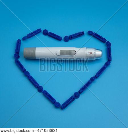 Lancet Pen Is Inside The Heart From Sterile Disposable Lancets Isolated On Blue Background. Sugar Le