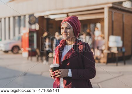 Modern Arab Girl In Hijab Walking By Street And Drinking Coffee Take Away In Spring Time Morning, Co