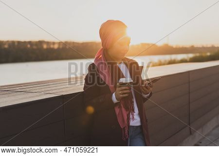 Modern Arab Girl In Hijab Walking By Street And Drinking Coffee Take Away In Spring Time Morning, Co