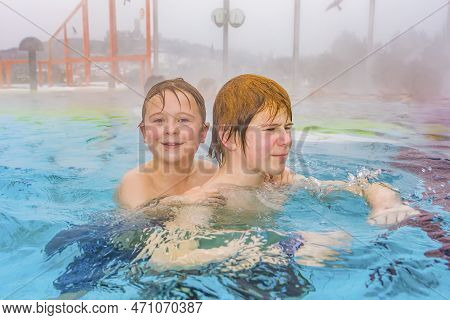 Brothers Are Swimming In The Outside Area Of A Thermic Pool In Wintertime In Warm Water, It Is Foggy