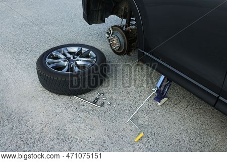 Car Lifted By Scissor Jack And New Wheel On Asphalt Outdoors. Tire Puncture