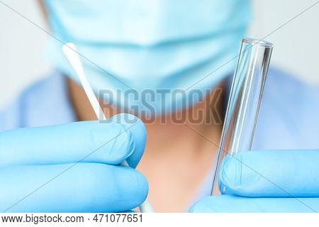 Doctor Holds A Covid-19 Swab Collection, Wears Blue Gloves And A Ppe Protective Mask, And Carries A 