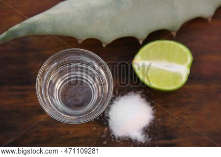 Mexican Tequila Shot, Salt, Lime And Green Leaf On Wooden Table, Flat Lay. Drink Made Of Agava