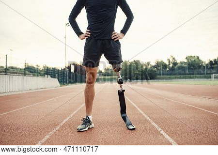 A Runner Standing On Running Track At Stadium With Hands On Hips.
