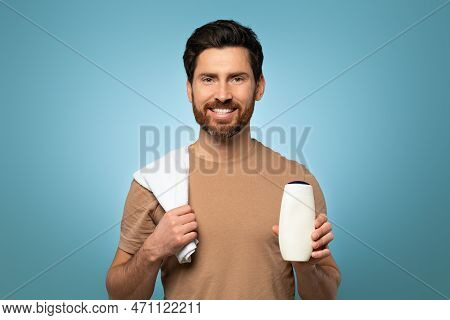 Handsome Happy Middle Aged Man With Towel At His Shoulder Holding Shampoo And Smiling, Standing On B