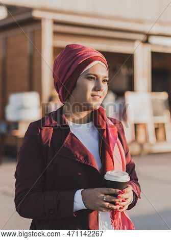 Modern Arab Girl In Hijab Walking By Street And Drinking Coffee Take Away In Spring Time Morning, Co