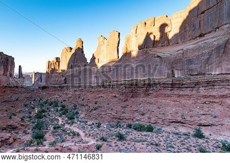 Hiking Trail Through The Dark Shadow Of A Canyon With Sagebrush In The Desert Landscape Of Arches Na