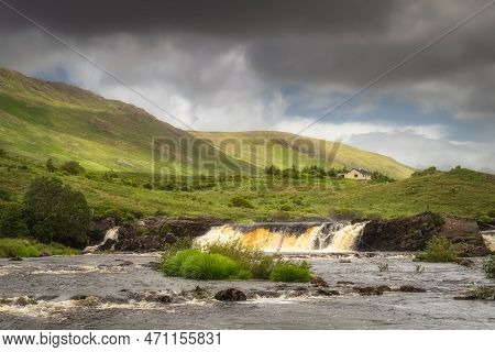 Aasleagh Falls On Erriff River With A Single House Under Letterass Mountains With Adrk Dramatic Sky 