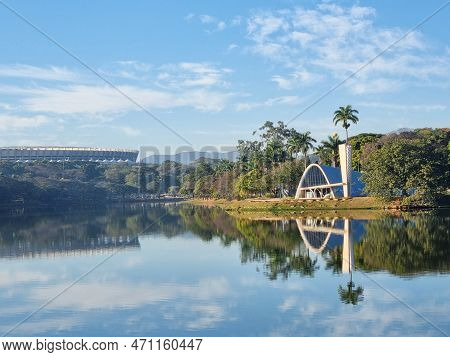 Pampulha Church Overlooking The Pampulha Lagoon, With Reflection In The Water And Blue Sky