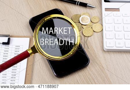 Market Breadth Text On Magnifier With Smartphone, Calculator And Coins