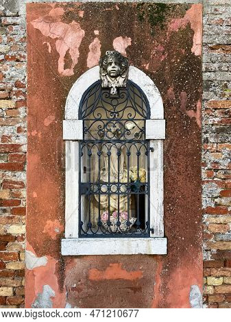 Outdoor Statue Of Madonna Behind Bars In Wall Of Old Residential City Building In Sestiere Of Cannar