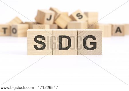 Text Sdg - Sustainable Development Goals - Is Written On Three Wooden Cubes Standing On A White Tabl